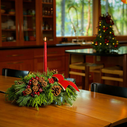 Christmas centerpiece with pine cones, gold balls and red berries with red velveteen bows and a red taper candle 