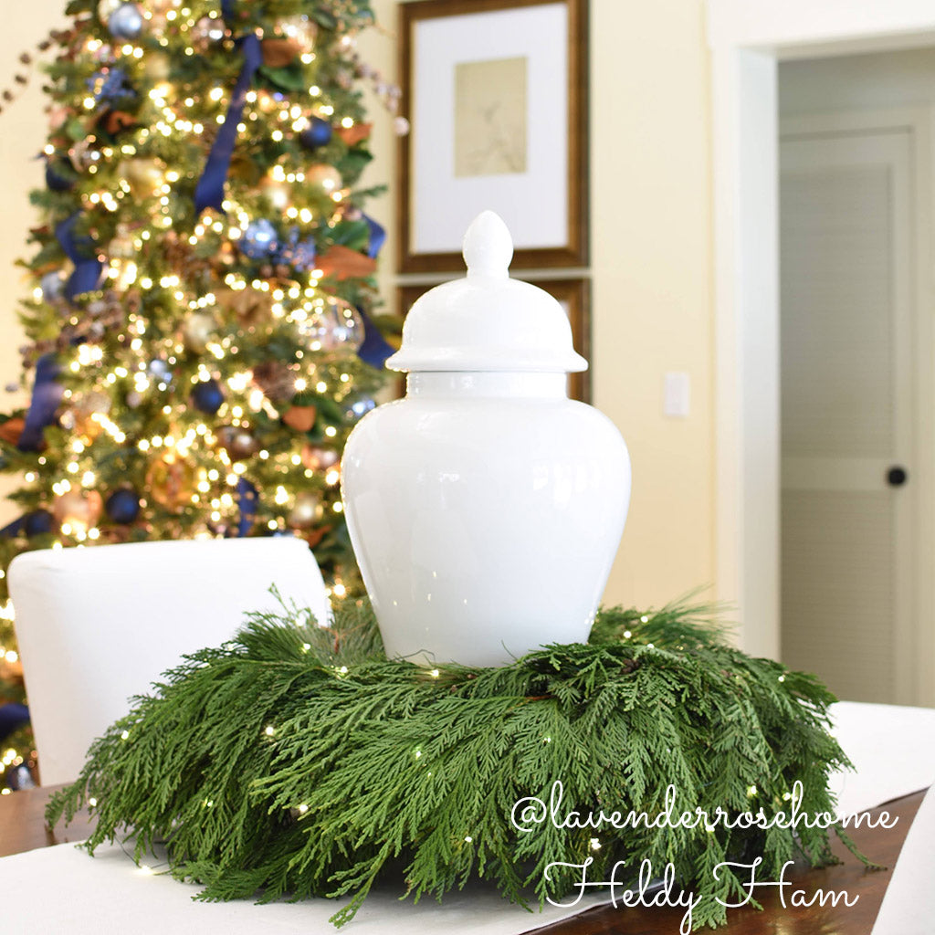 Christmas wreath with cedar and pine used around the base of a vase as a centerpiece.