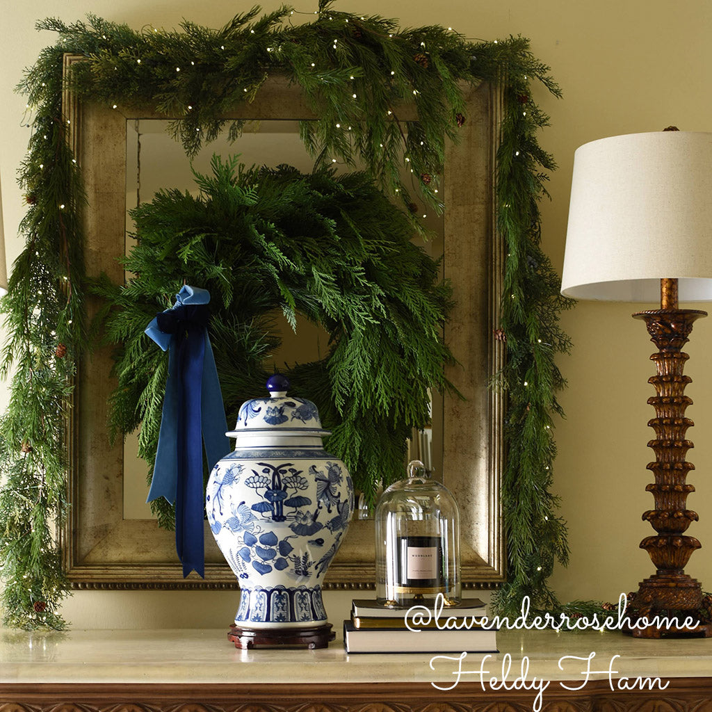 Christmas wreath with cedar and pine hanging inside with garland and lights.