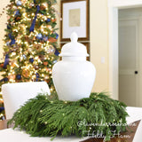 Christmas wreath with cedar and pine used around the base of a vase as a centerpiece.