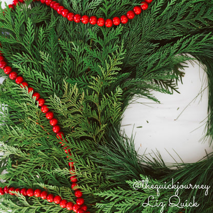 Christmas wreath with cedar and pine close up with red beads.