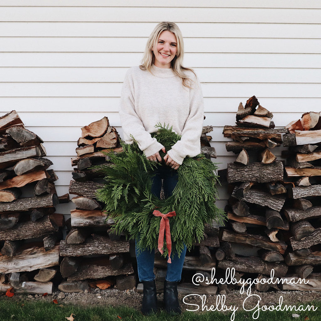 Christmas wreath with cedar and pine held by a person.