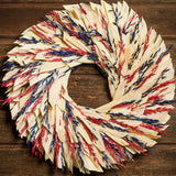 22" wreath made of red and blue oats and natural corn husk on a dark wood background.