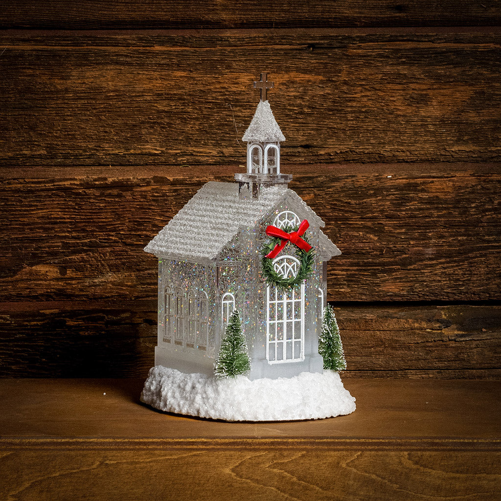 Lighted Church water globe with a dark wooden background.