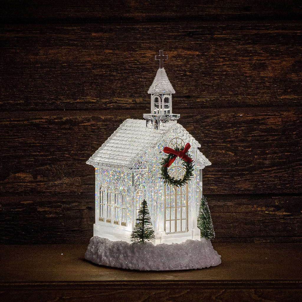 Lighted Church water globe with a dark wooden background.