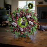 Christmas wreath made of noble fir, cedar, white pine, and bay leaves with 9 frosted Australian pine cones, and a ring of frosted branches with faux burgundy berries on wreath stand