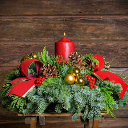 Centerpiece with pine cones, gold balls, red berry clusters,gold trimmed red bow tucks and a red pillar candle